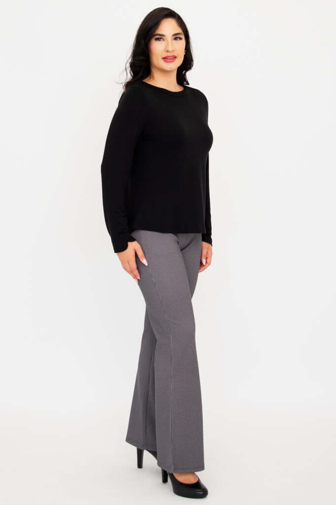 Woman showing black long sleeve boat neck top and gray check pants, side view