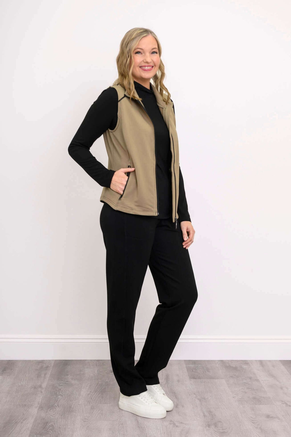 Side view of woman wearing tan Hartford Utility Vest and black pants
