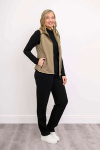 Side view of woman wearing tan Hartford Utility Vest and black pants