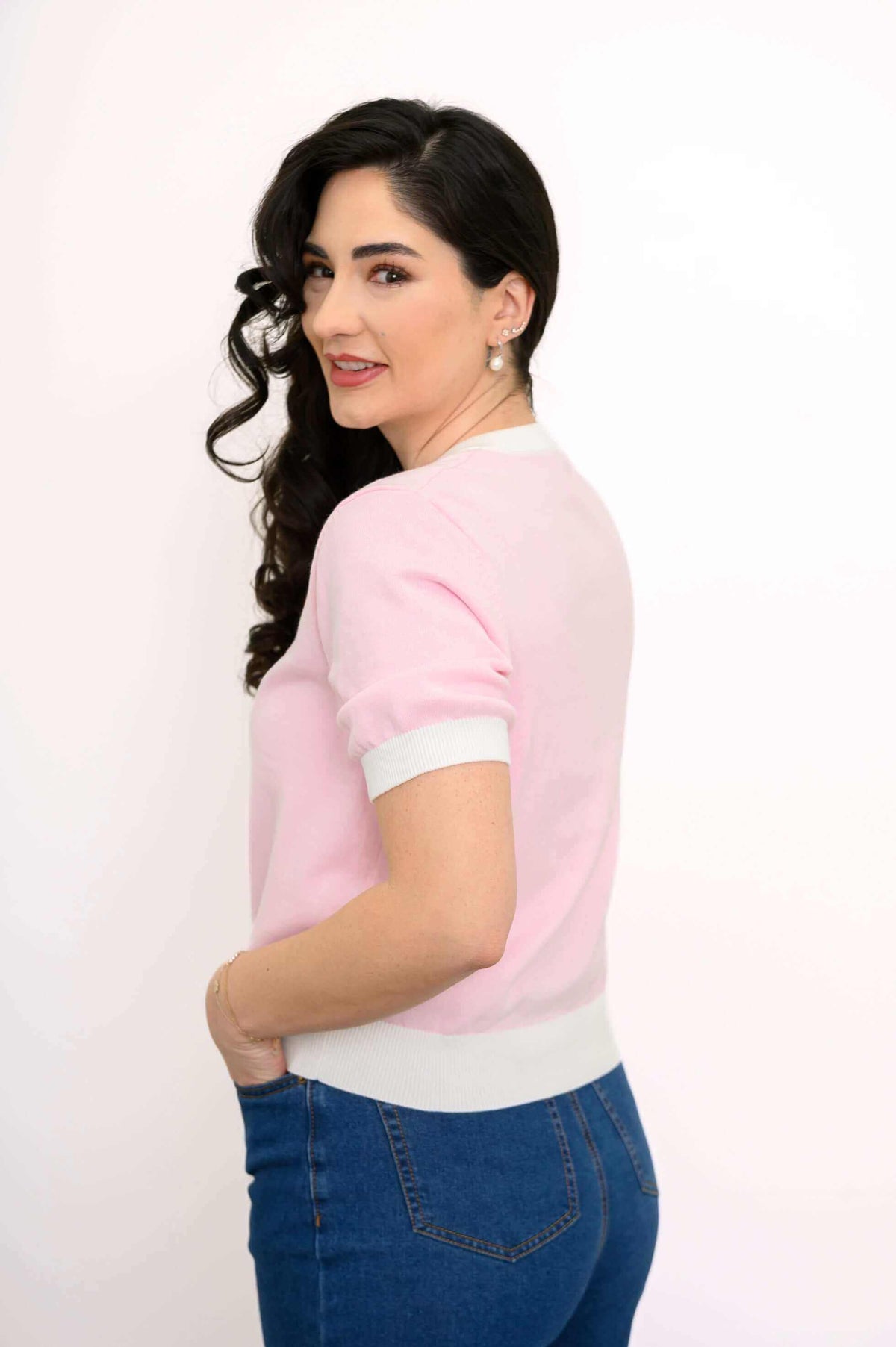Side view of woman in retro pink sweater with short sleeves and ribbed trim