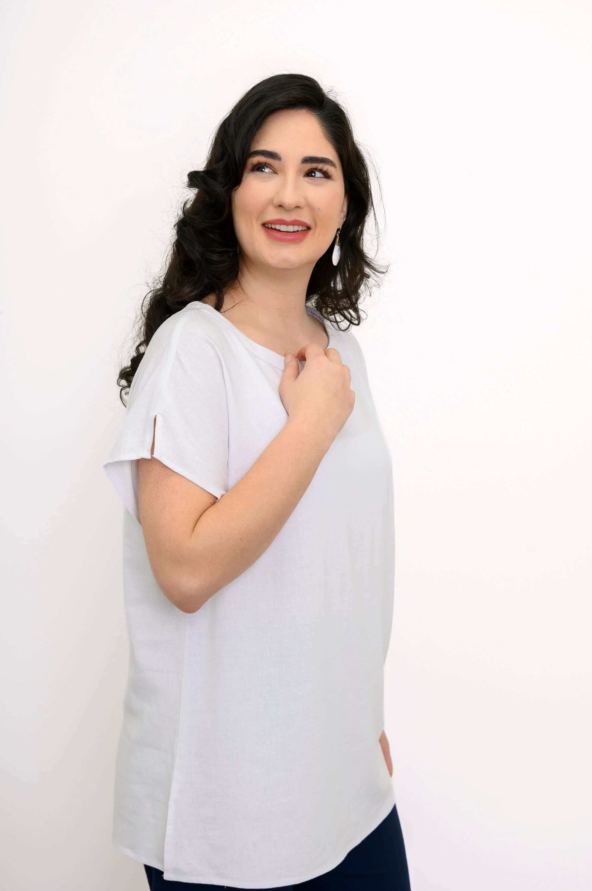 Side angle of woman in white dolman sleeve tee with slit at shoulder seam