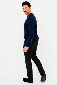 Side view of a man smiling and wearing a navy sweater with black pants