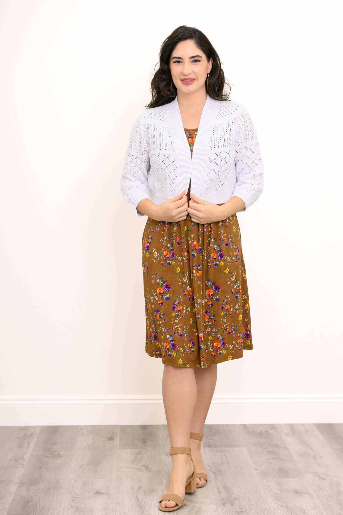 Woman wearing a white knit cardigan over a brown floral dress
