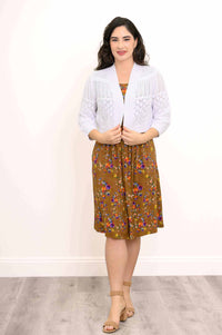 Woman wearing a white knit cardigan over a brown floral dress