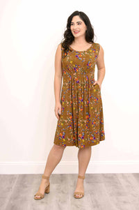 Woman standing with one hand in the pocket of a brown floral dress