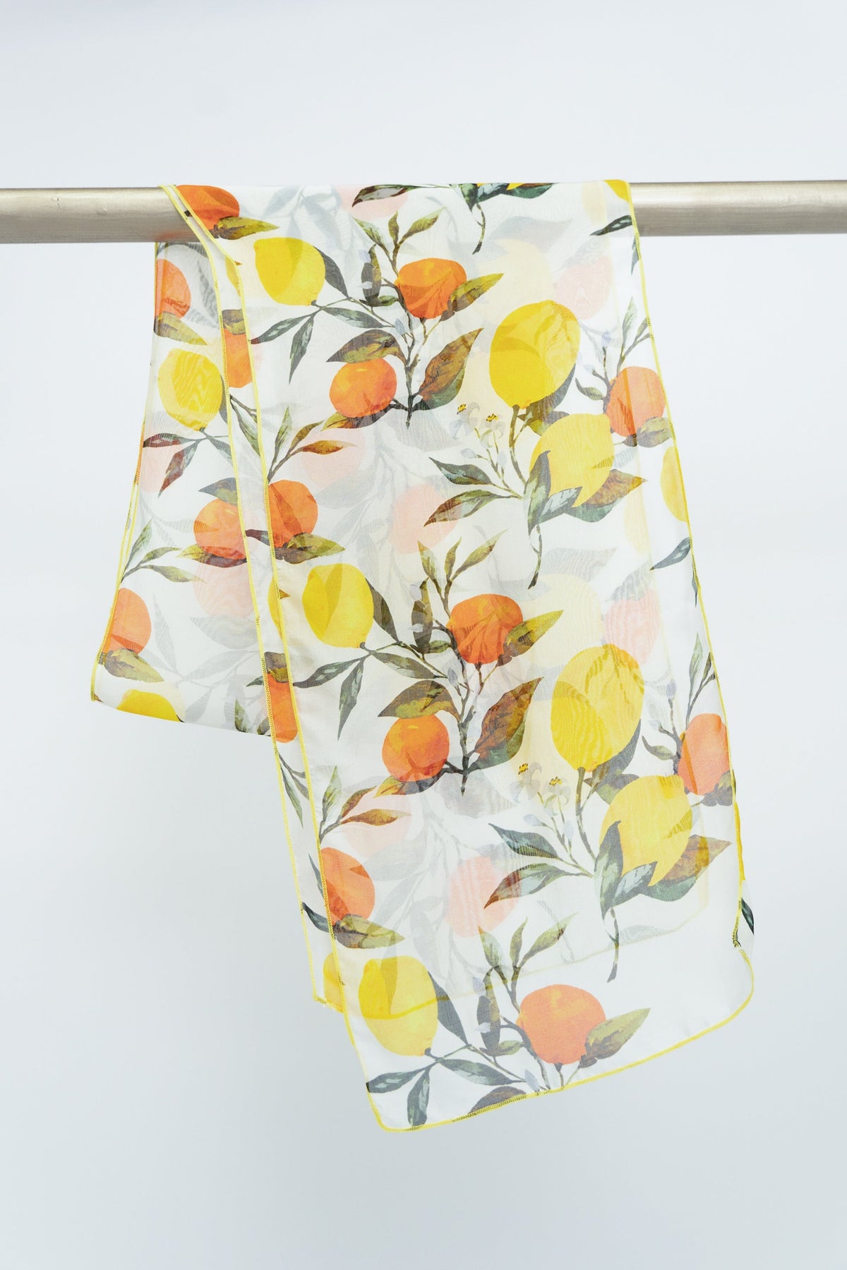 A silk scarf with a lemon and orange print, displayed on a rod against a white background, front view