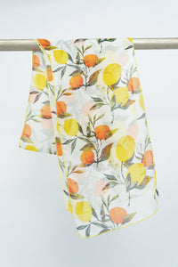 A silk scarf with a lemon and orange print, displayed on a rod against a white background, front view