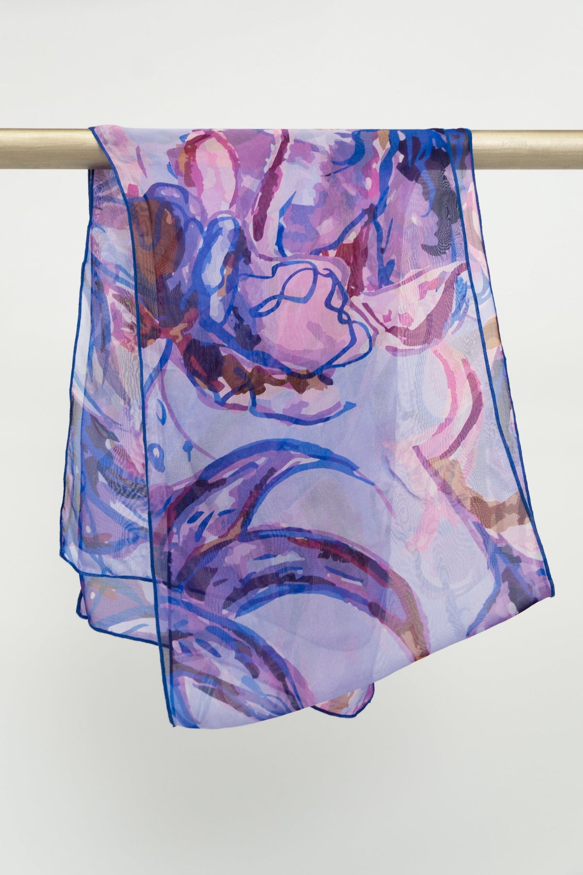 A large silk scarf with a painted floral pattern in shades of purple, displayed on a rod, front view