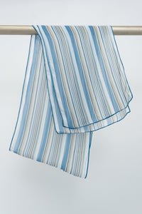 A large silk scarf with a blue and white striped pattern hanging on a rod, front view