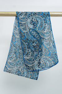 A blue and white paisley patterned silk scarf draped over a metallic rod, front view