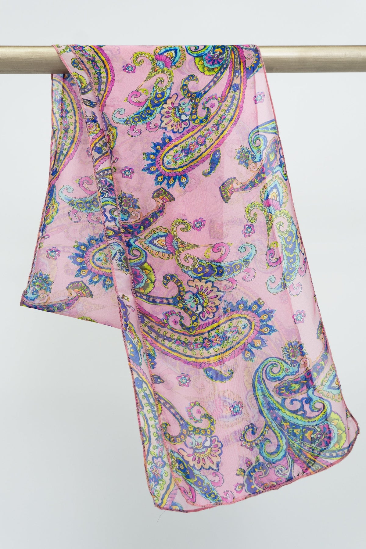 A large pink silk scarf with a yellow and blue paisley pattern, displayed on a rod against a white background, front view