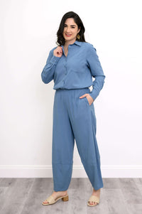 Woman wearing sky blue shirt tucked into matching pants, smiling