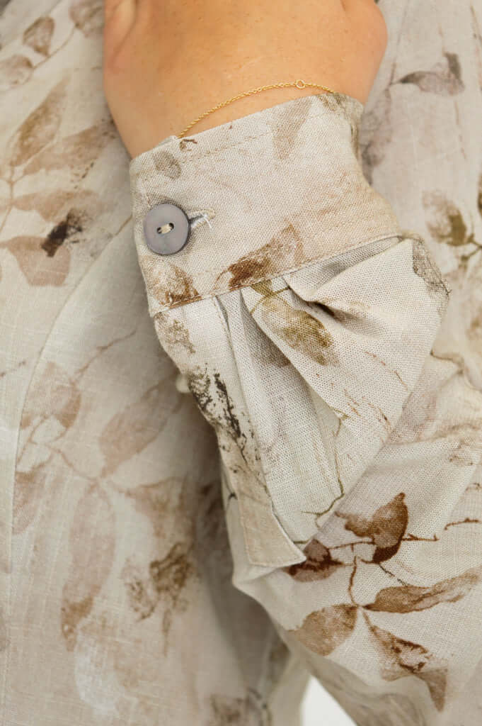 Close-up of blouse sleeve with button and pleat detail in floral fabric