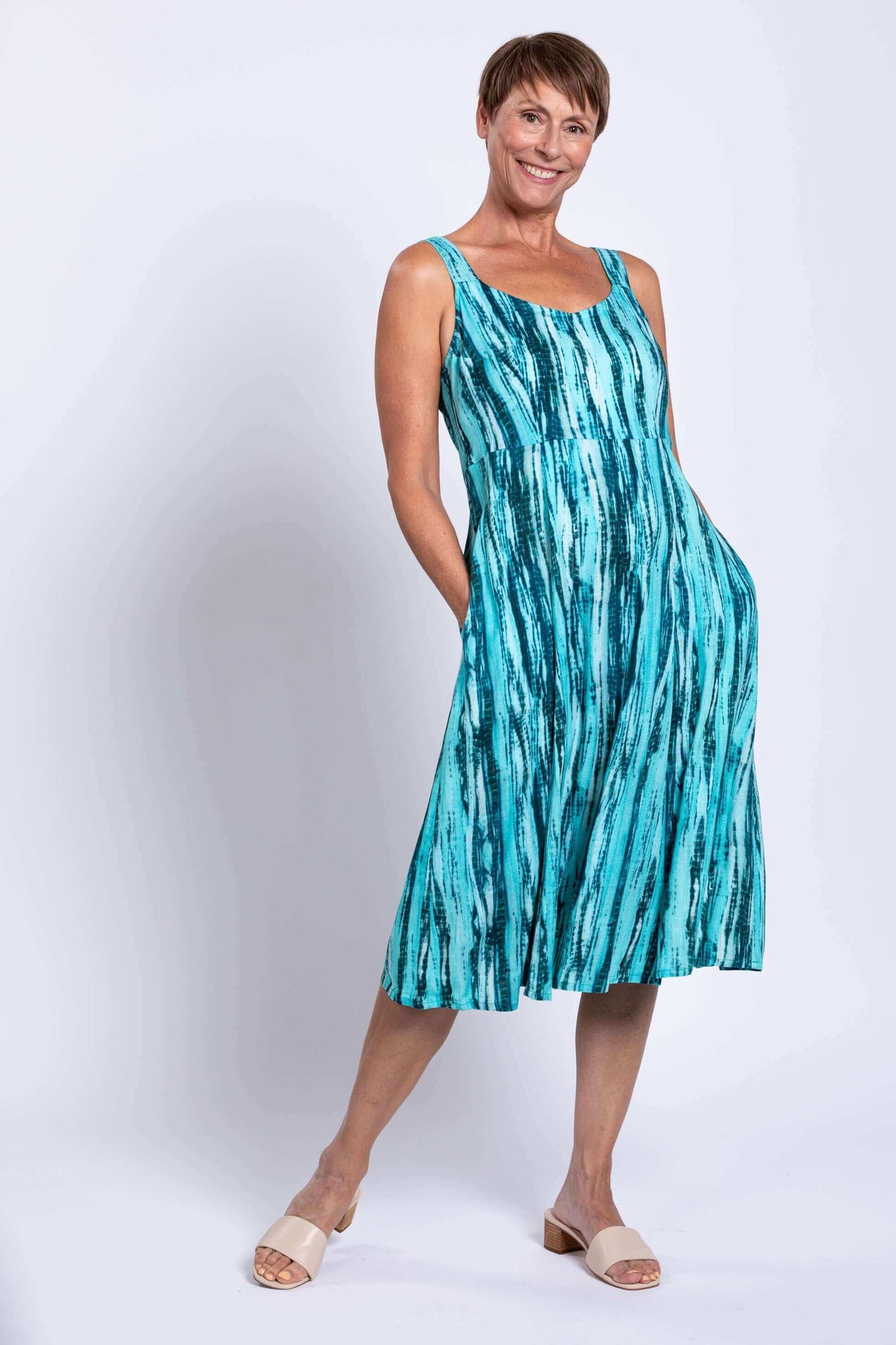 Woman in sleeveless aqua streak A-line dress posing with hands in pockets