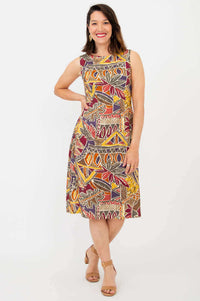 Woman wearing sleeveless dress with abstract tribal print, standing and smiling