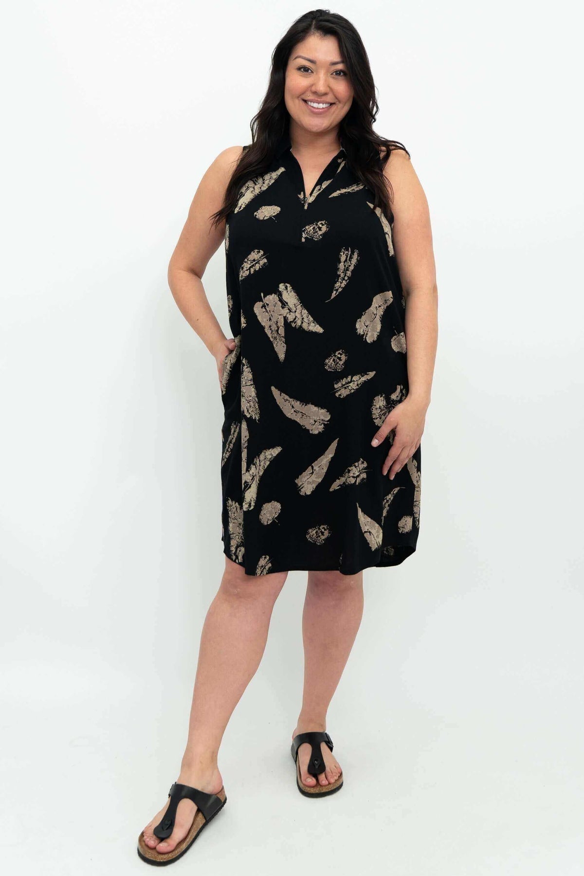 Woman wearing sleeveless black dress with tan feather print and zippered collar