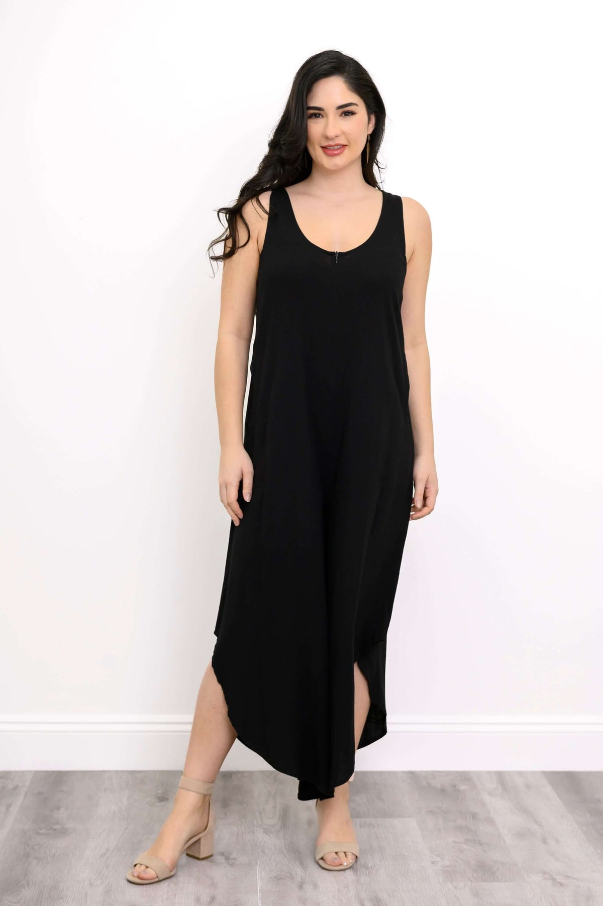 Model wearing sleeveless black jumpsuit with cropped asymmetrical hem