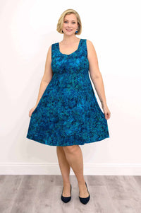 Woman modeling sleeveless blue A-line dress with tropical pattern and heels