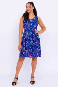 Model showing sleeveless blue floral dress from the front with hand on hip