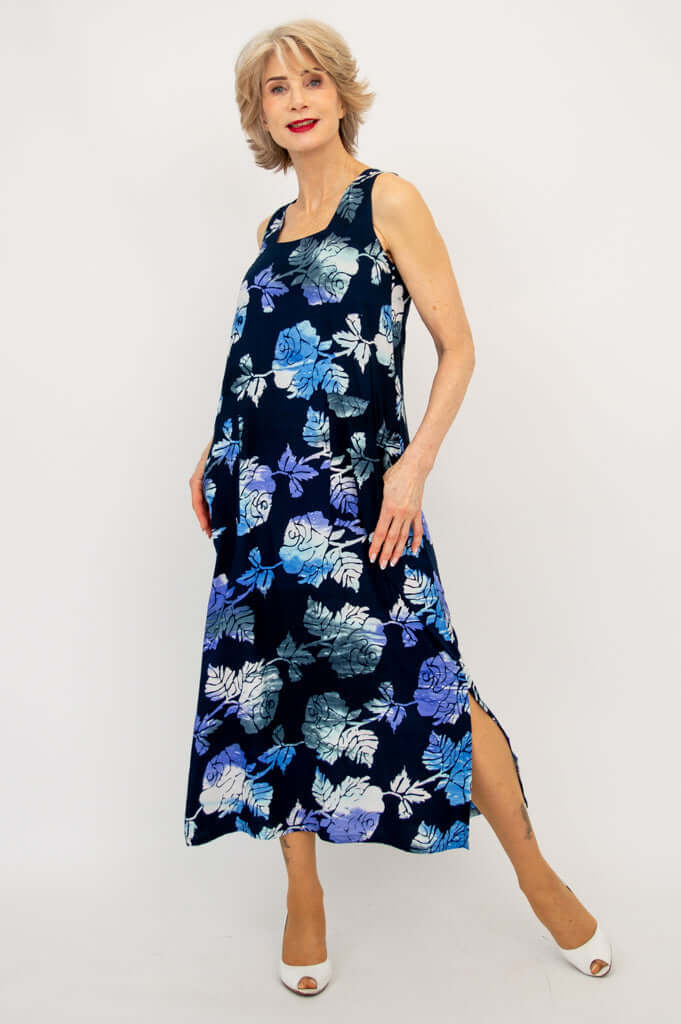 Sleeveless blue floral dress with side slit, modeled by woman stepping forward