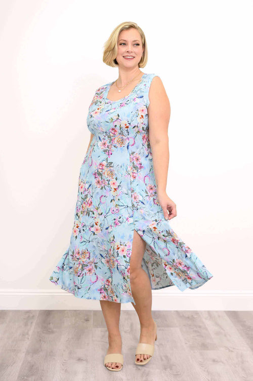 Woman in a sleeveless blue floral midi dress showing front slit detail
