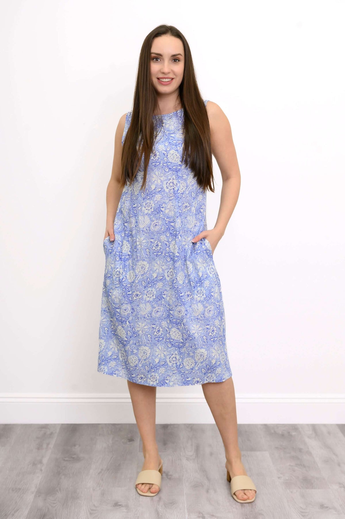 Woman in blue paisley sleeveless midi dress with hands in pockets