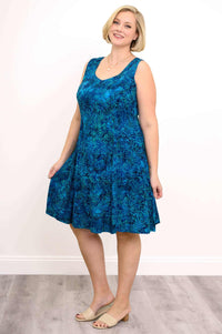 Model wearing a sleeveless blue plus size A-line dress with tropical leaf print