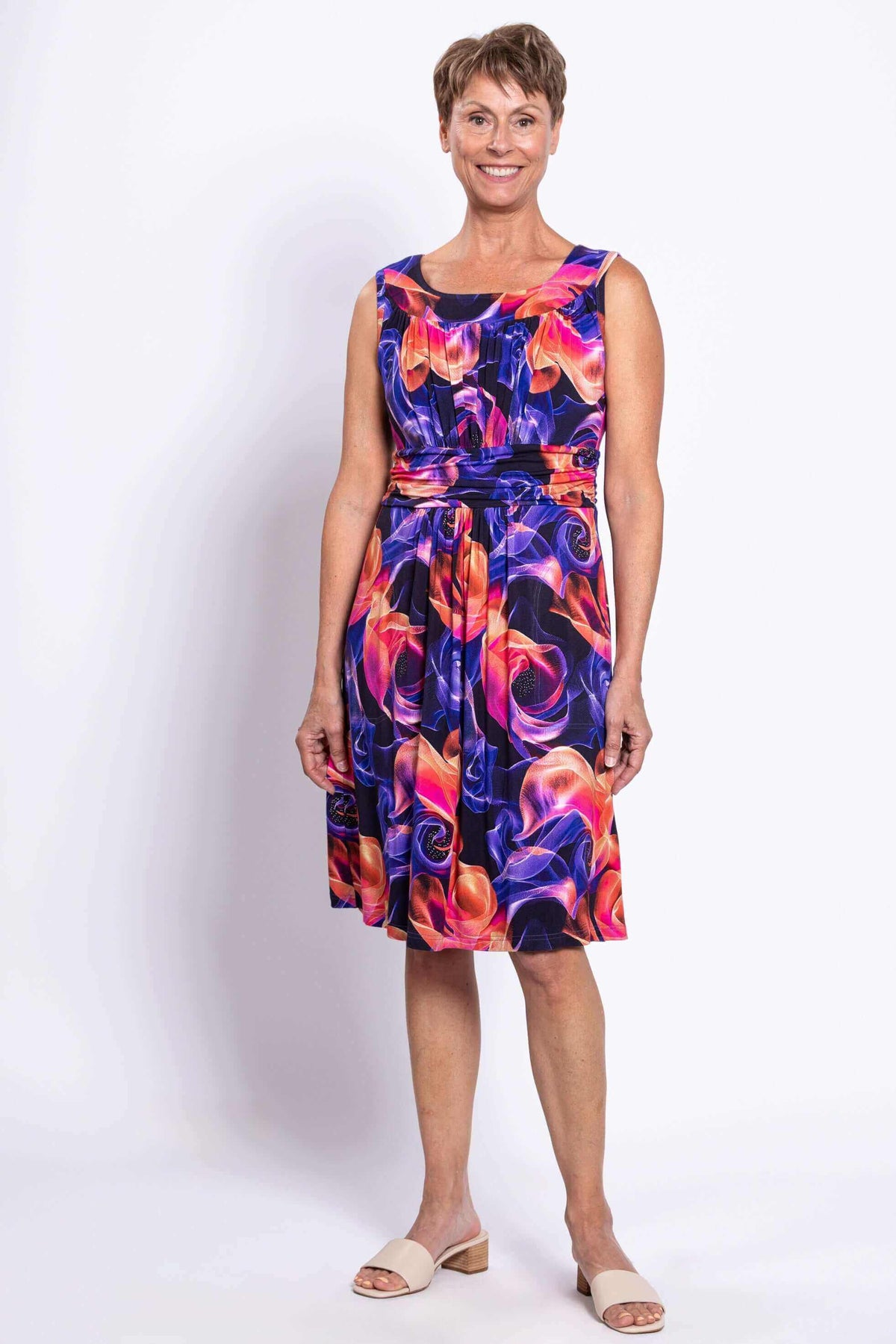 Woman wearing a sleeveless knee-length dress with a vibrant floral swirl pattern