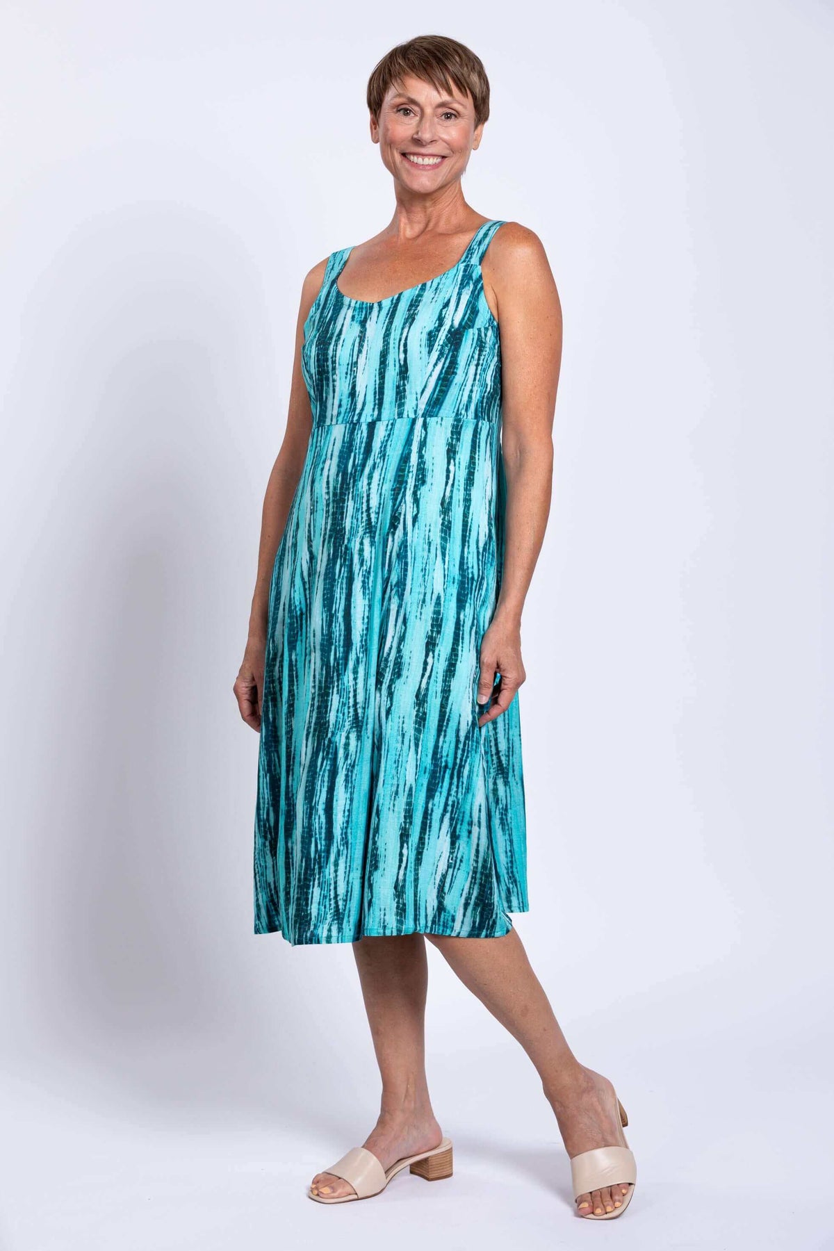 Woman modeling an aqua streak sleeveless dress with an empire waist and A-line skirt