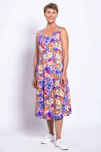 Woman smiling in a sleeveless, floral print dress with bright purple and orange flowers