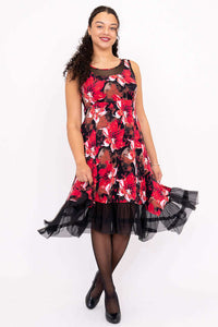 Woman wearing a sleeveless floral dress with mesh hemline twirling against white background