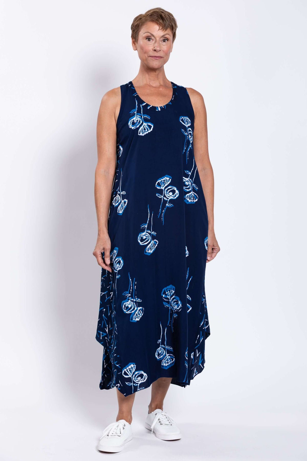 Woman standing in a navy blue sleeveless tank dress with white and blue flower pattern, front view