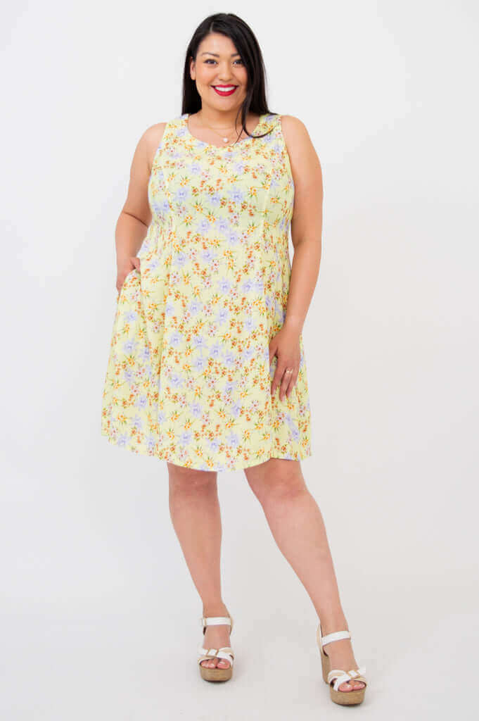 Front view of another model in a sleeveless yellow floral dress with pockets