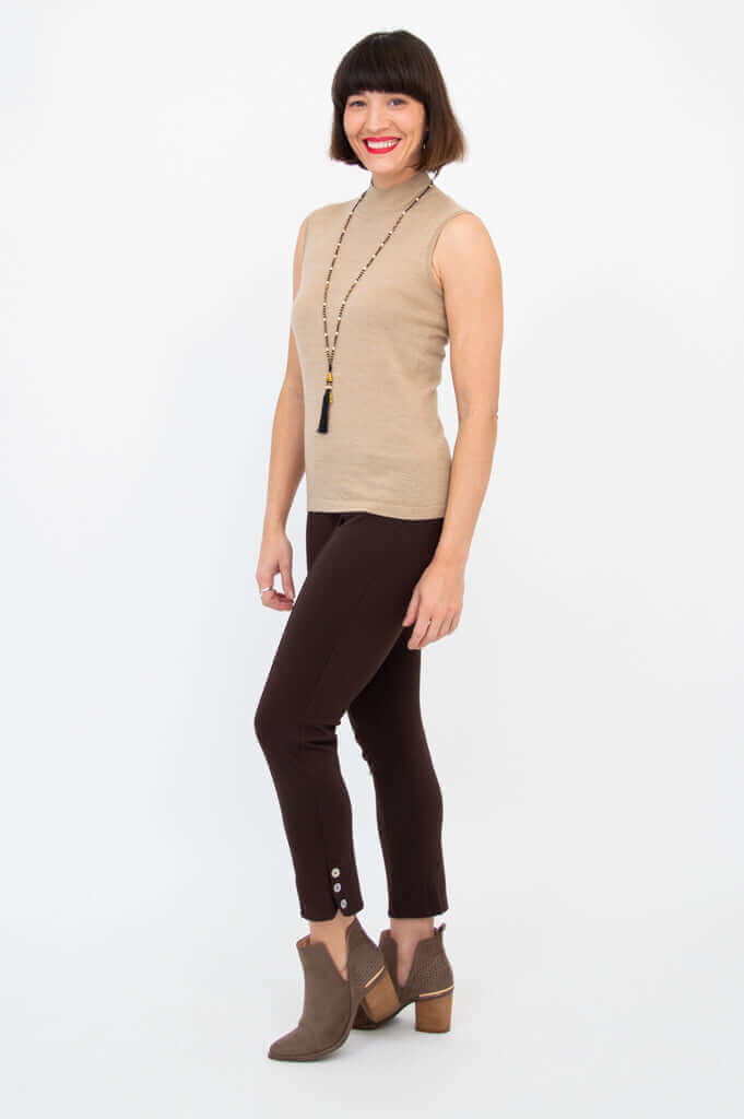 Woman posing in sleeveless tan sweater with slim fit and brown pants