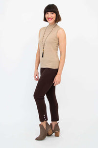 Woman posing in sleeveless tan sweater with slim fit and brown pants
