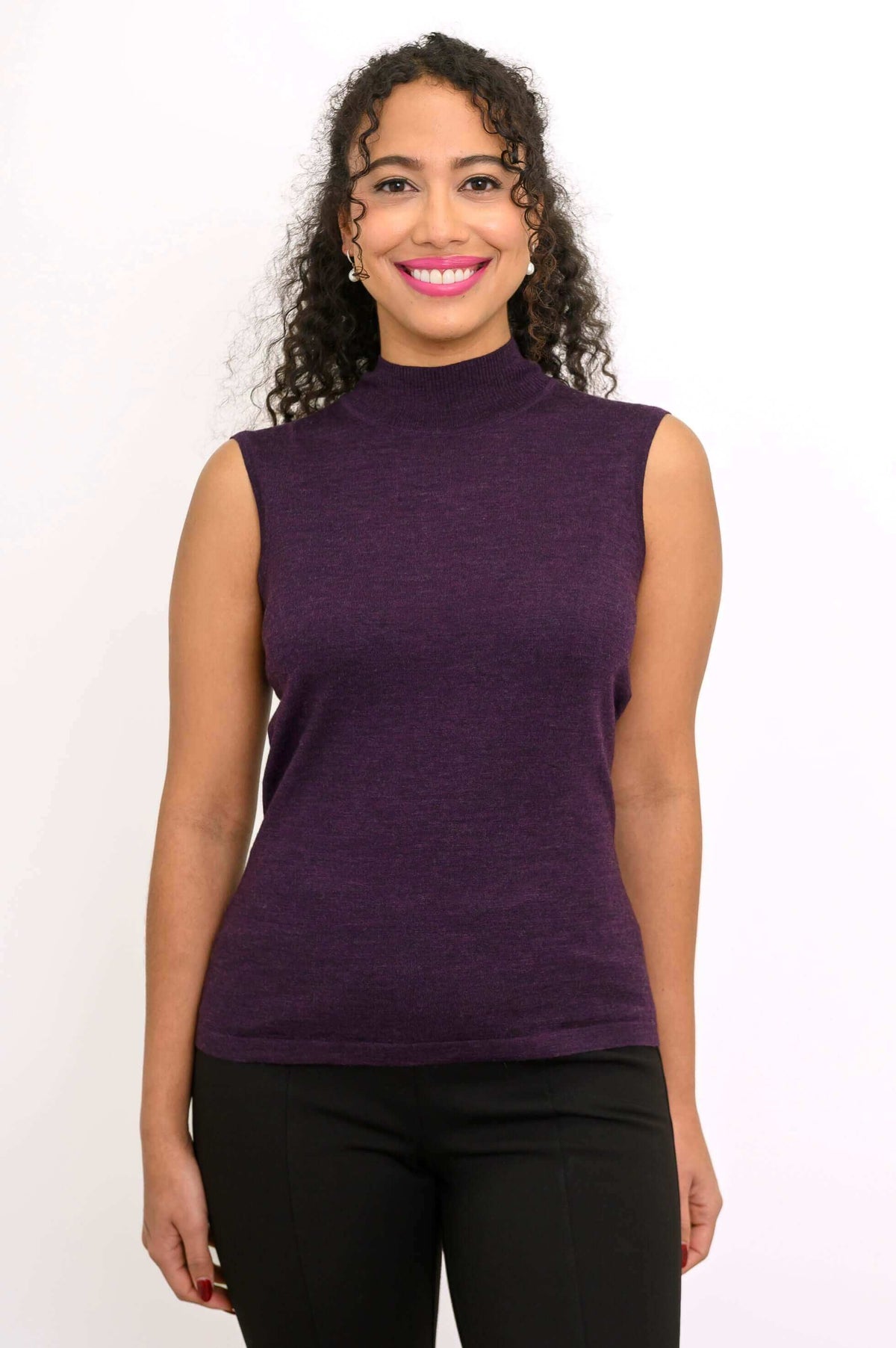 Woman smiling and wearing purple sleeveless mock neck Merino wool sweater