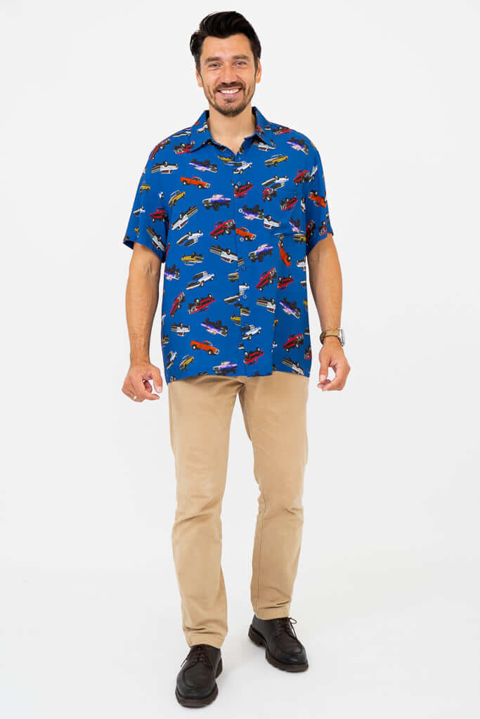 Man smiling in blue monster truck print shirt and beige pants, front view
