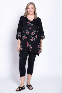 Woman smiling and modeling a flowy black blouse with modern abstract designs