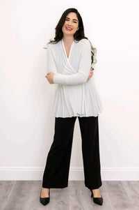 Woman crossing arms and smiling in white Karen Cardigan and black pants