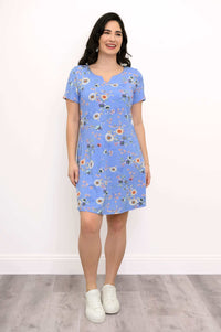 Model smiling in blue floral knee-length dress with short sleeves and white sneakers
