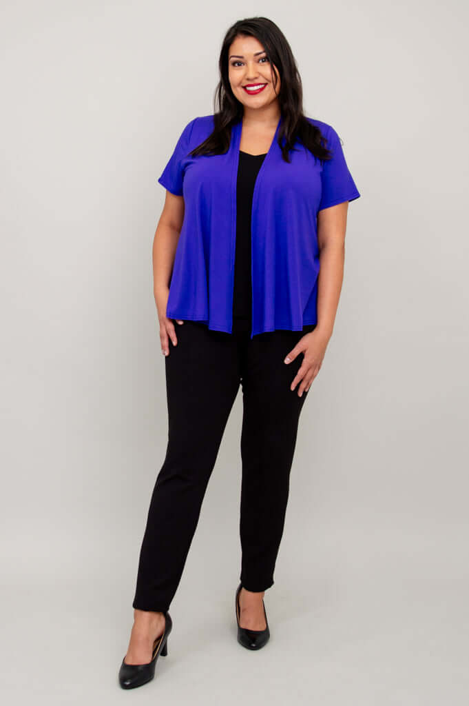 Model wearing a vibrant purple short sleeve jacket and black pants, smiling