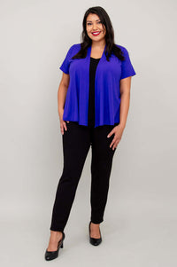 Model wearing a vibrant purple short sleeve jacket and black pants, smiling