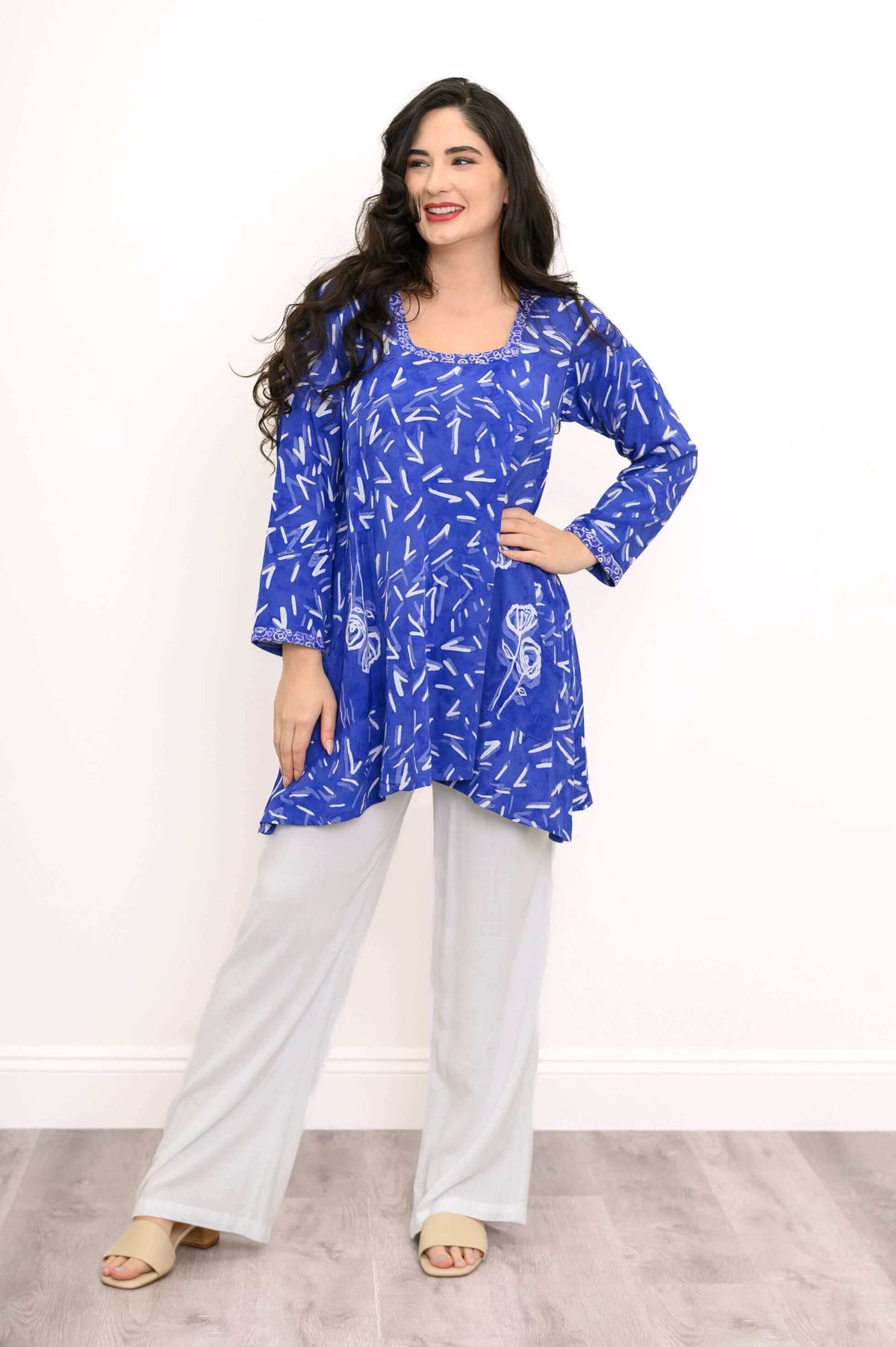Woman smiling in blue Maria tunic with white accents and patch pockets, hands on waist