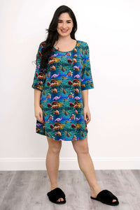 Smiling woman modeling a bamboo sleepshirt with turtles and coral reef pattern, hands by sides