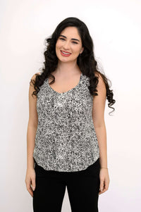 Woman smiling in black and white rose-printed tank top, front view