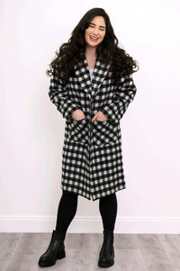 Front view of smiling woman in a checkered wool coat with hands in pockets