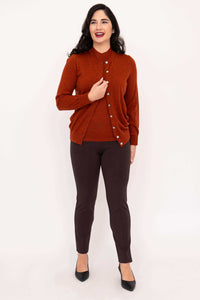 Woman wearing rust Merino wool cardigan smiling with hand to chest