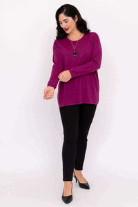 Woman smiling and looking down in a vivid pullover sweater and black pants