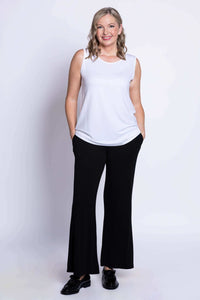 Smiling woman in white French Terry tank with hands in black pants pockets