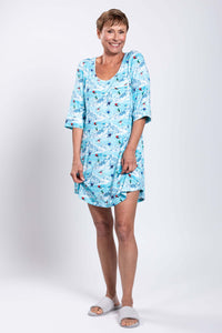 Woman smiling and posing in a blue skier-pattern sleepshirt with slippers